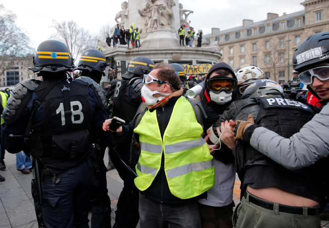 Riot police and members of the media are seen amongst protesters on the sidelines of a demonstration by the French "yellow vests" movement against police violence in Paris